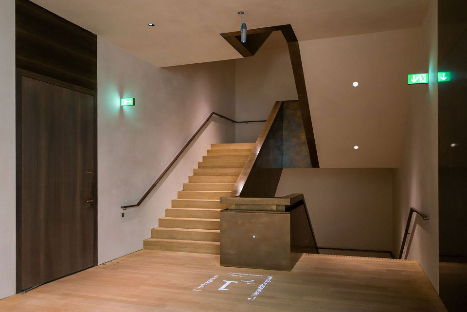 Treppenhaus mit einem Deckenprojektor, der eine Wegweisung auf den Holzboden wirft