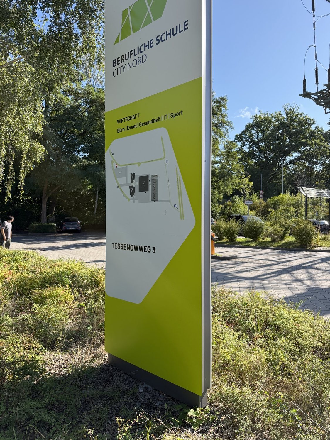 Monolith der Beruflichen Schule City Nord am Tessenowweg: grauer Kopf mit Logo und Schulname über grünem Korpus mit Lageplan und Adresse.