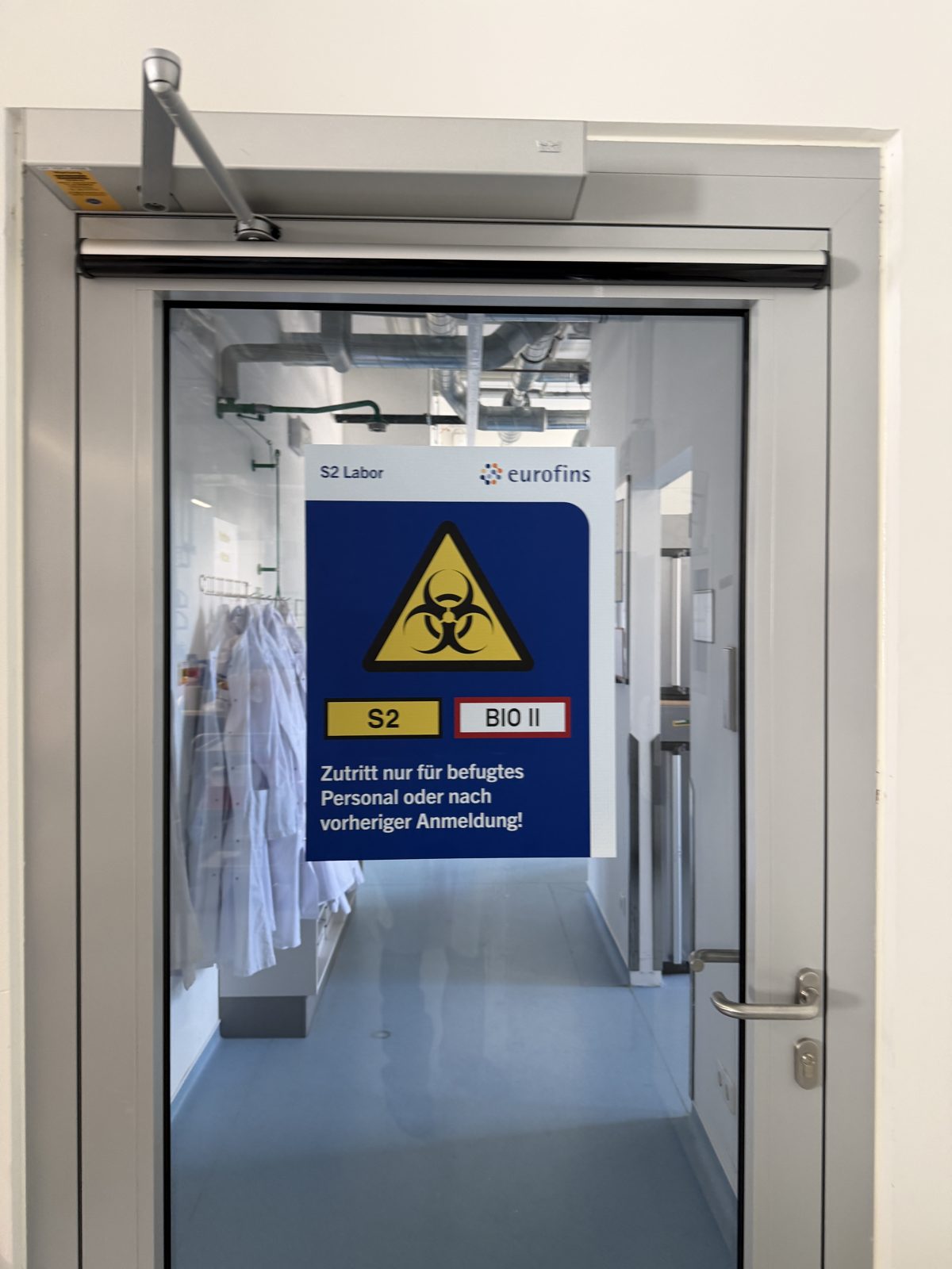 Glastür im Laborbereich mit einem Hinweisschild zur Biogefährdung