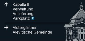 Wegweiser 3, Vorderseite: Pfeil ↑ Kapelle II, Verwaltung, Anlieferung, Parkplatz; Pfeil → Alstergärtner, Alevitische Gemeinde