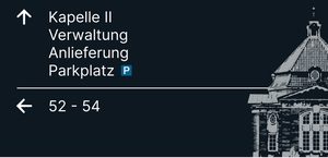 Wegweiser 4, Vorderseite: Pfeil ↑ Kapelle II, Verwaltung, Anlieferung, Parkplatz; Pfeil ← 52–54