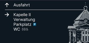 Wegweiser 6, Rückseite: Pfeil ↑ Ausfahrt; Pfeil → Kapelle II, Verwaltung, Parkplatz, WC