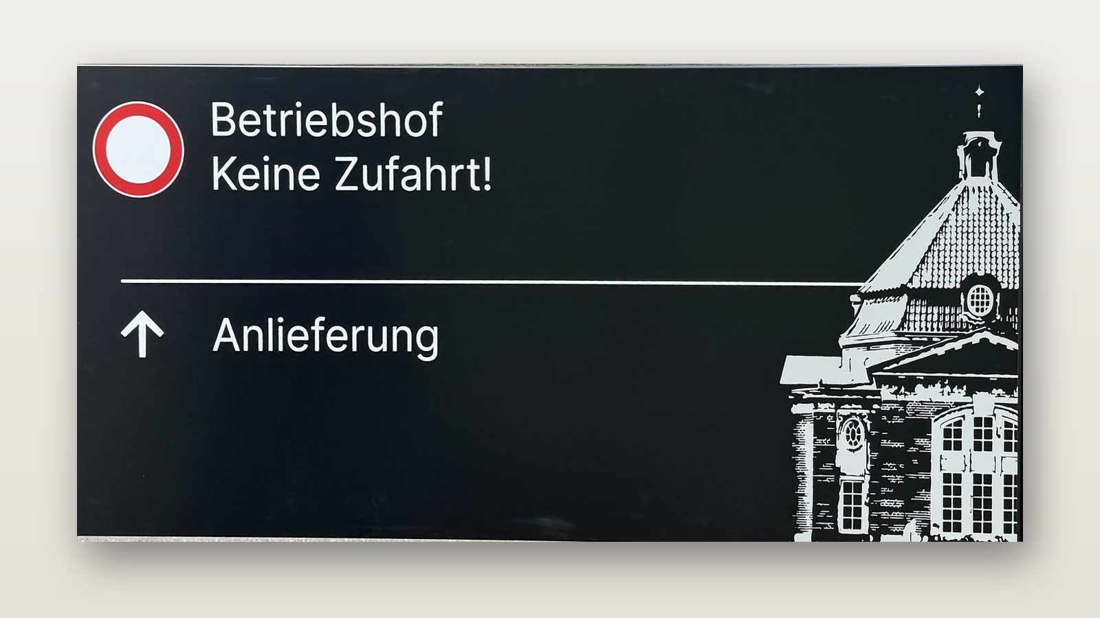 Wegweiser in Schwarzblau, freigestellt: rundes Verbotszeichen mit Betriebshof, Keine Zufahrt!, darunter Pfeil zur Anlieferung
